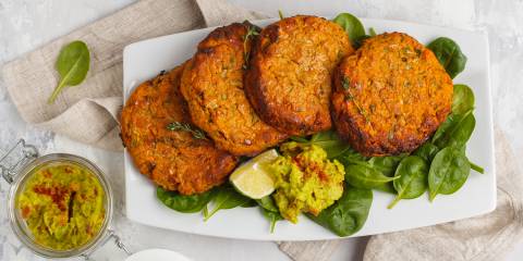 Sweet Potato and Mustard Turkey Burgers on a white platter on a bed of spinach greens.