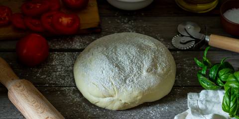 a ball of floured pizza dough and other ingredients