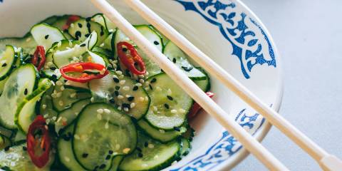 Chopsticks resting on a bowl of Thai cucumber salad