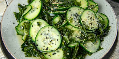a plate of cucumber with oil, vinegar, wakame flakes, and sesame
