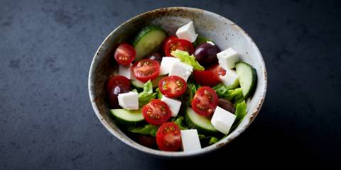 a bowl of greek salad with cucumbers, olives, and cherry tomatoes