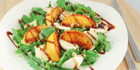 A plate of arugula with peaches and mozzarella