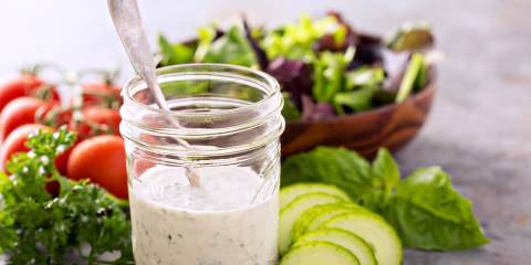 a mason jar of homemade ranch dressing, plus salad greens and veggies for dipping