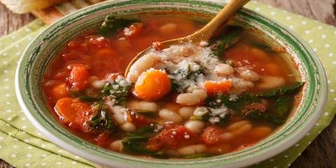 a bowl of tomato-based soup with beans and spinach