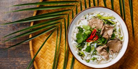Pho Bo vietnamese Soup with beef on bamboo tray on wooden background.