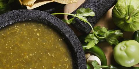 a bowl of salsa and some fresh tomatillos