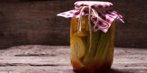 A jar of pickled zucchini on a rustic farm table.