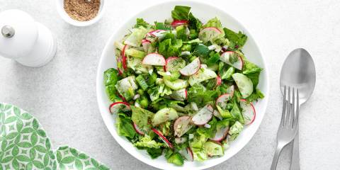 a bowl of green salad with radishes