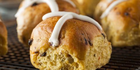 Close up of a few hot cross buns with frosted decorative cross on top.