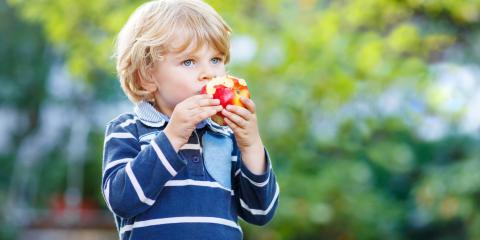 Child outside eating a red apple. 