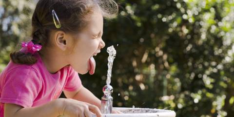 a little girl drinking from a bubbler fountain