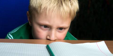 A child staring helplessly at his blank schoolwork