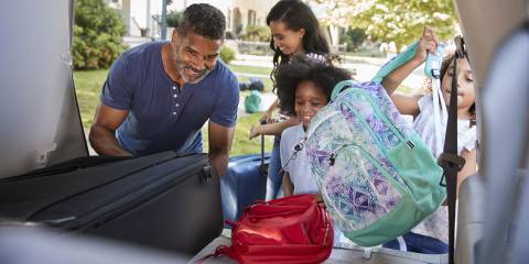 a family packing the car for a vacation, including a red bag