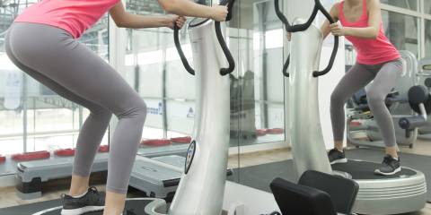 a woman using a vibration platform in the gym