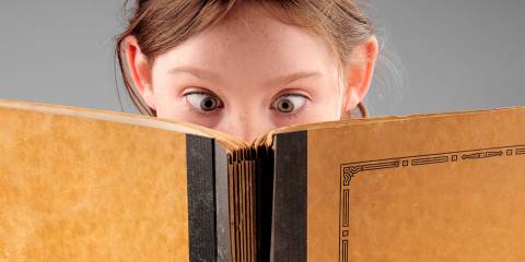 a cross-eyed child reading a book