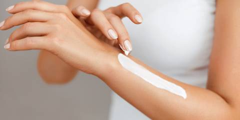 a woman applying skin lotion to her arm