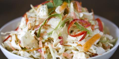 White bowl of green cabbage and bell pepper cole slaw.