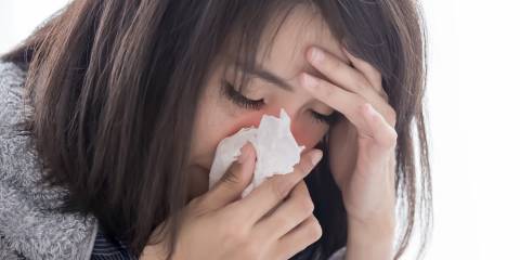 a stressed woman sneezing into a tissue