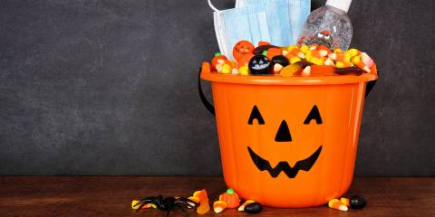 a trick or treat pail with sanitizer and a mask