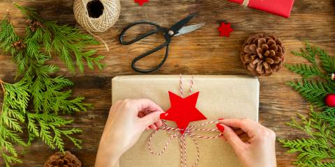 tying a string bow on a gift wrapped in craft paper.