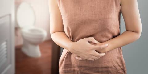 A woman outside the bathroom with bowel cramps from bloating