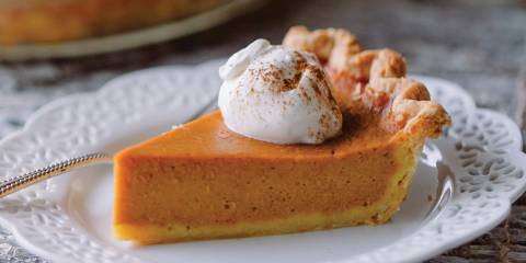 a slice of pumpkin pie with a dollop of whipped cream