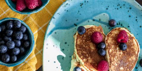 a plate of pancakes and bowls of berries