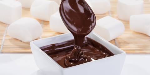 thick chocolate sauce drizzling from spoon to bowl