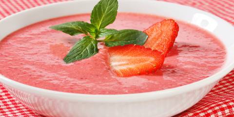 a cold bowl of creamy strawberry soup garnished with mint