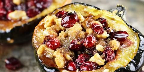 An acorn squash half stuffed with meat, dried cranberries, and walnuts.