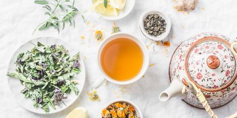 a cup of tea, a teapot, and detoxifying herbs