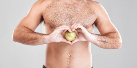 a healthy bare-chested man holding an apple