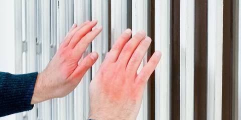 a frostbitten man warming his hands near a radiator