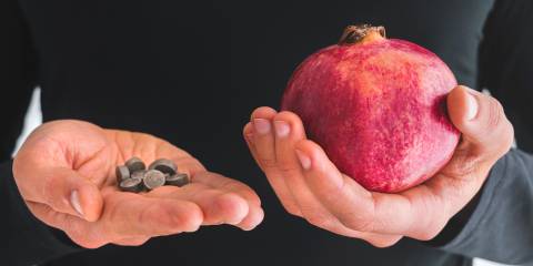 a man holding iron supplements and a pomegranate