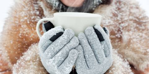a young woman holding a steaming mug with winter gloves