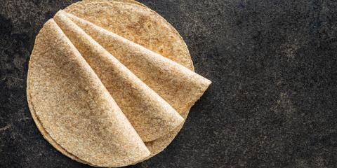 Several whole-grain tortillas folded on a gray granite surface.