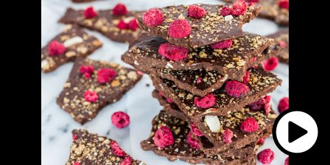 A stack of chocolate bark with raspberries and crispy almond and grain flakes