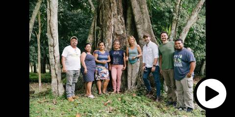 Caroline standing at the edge of a rainforest with some of her workers and farmers