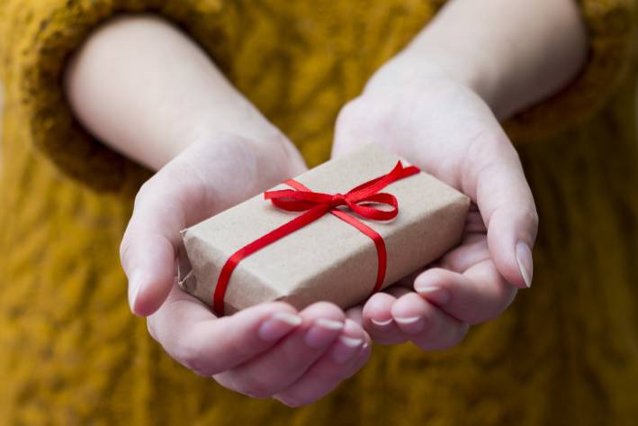 a woman holding out a small gift