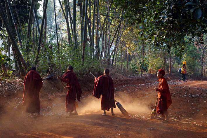 young monks sweeping the dirt yard