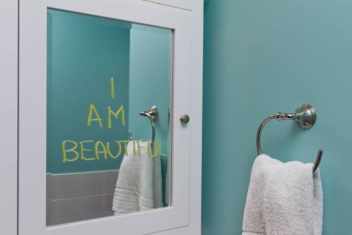 A bathroom mirror with "I am beautiful" written on it.