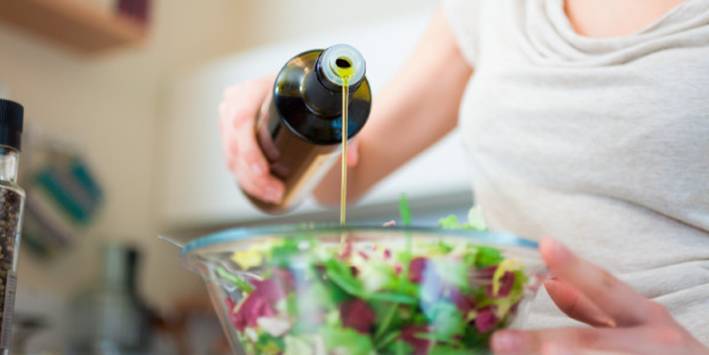 Woman pouring dressing in a salad bowl