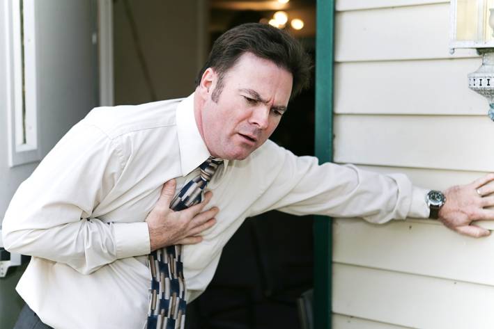 A man grabbing his chest during an agina episode.