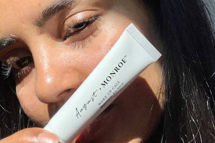 a woman with beautiful eyes holding up a tube of serum