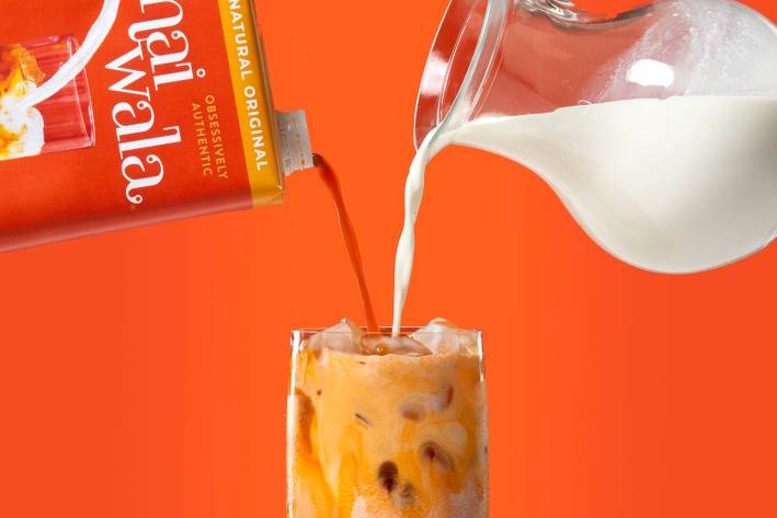 Milk and thai tea being poured into a glass