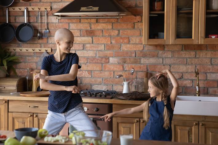a young woman with cancer, dancing in the kitchen with her daughter