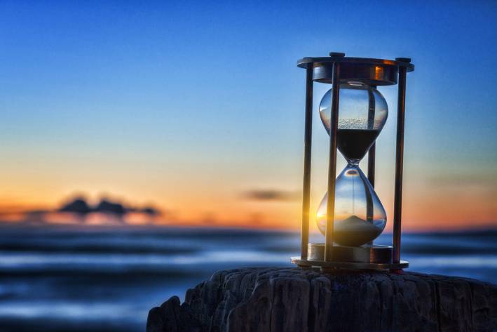 sunset shining through an hourglass on the beach