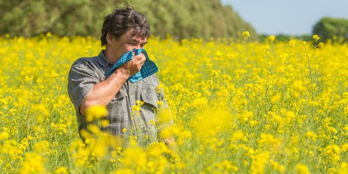 Man wiping his nose in a field of flowers