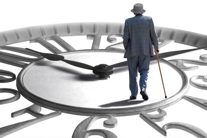a senior man with a cane walking across a giant clock
