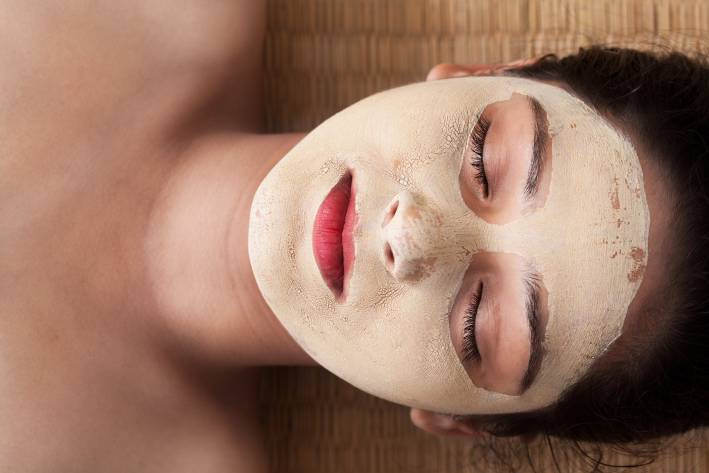 An indian woman with closed eyes relaxing and having an Ayurvedic face mask